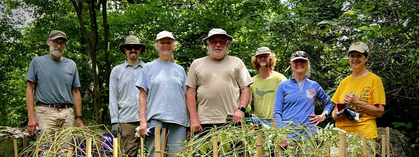A group of 7 volunteers standing in the native plant trail woodland