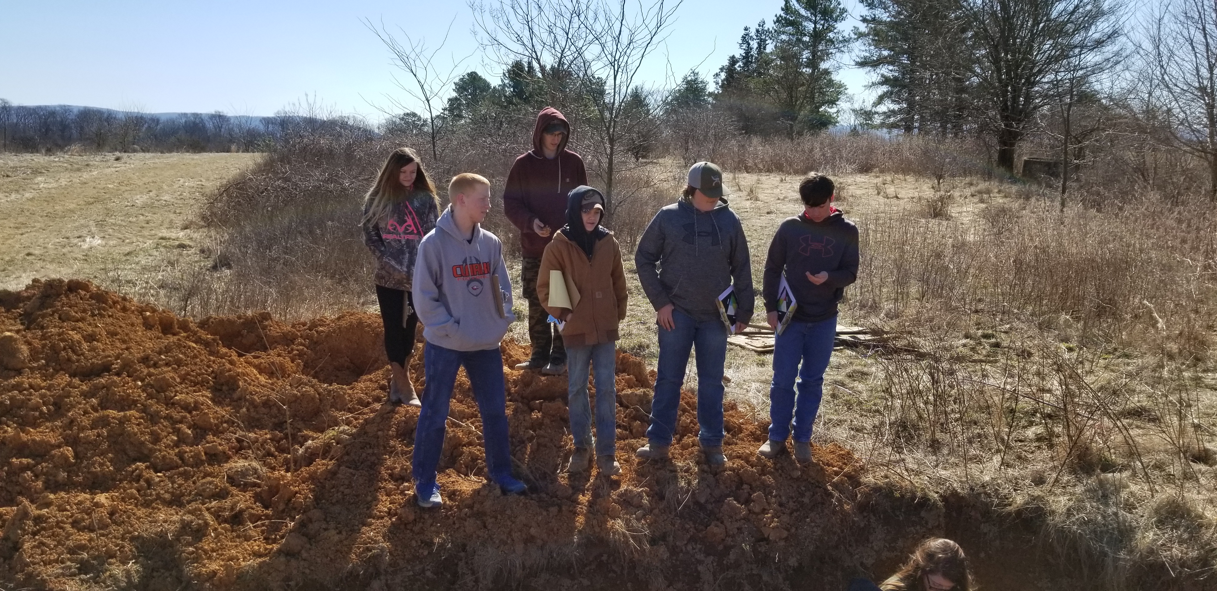 High school students gaze into a soil profile