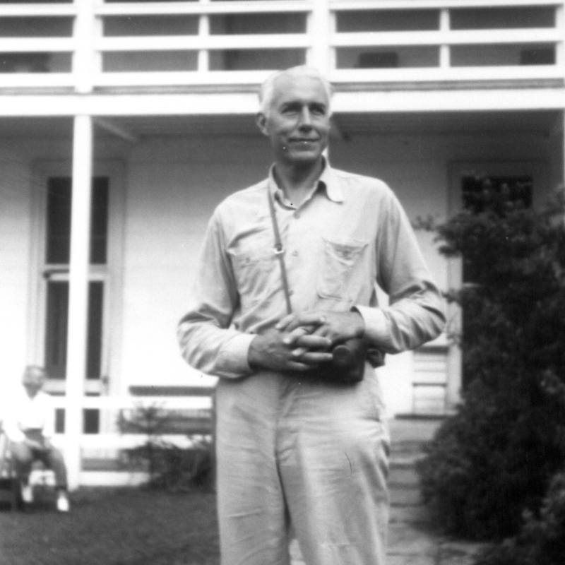 Black and white photo of Dr. Flory stands in the courtyard of the Quarters Buliding.