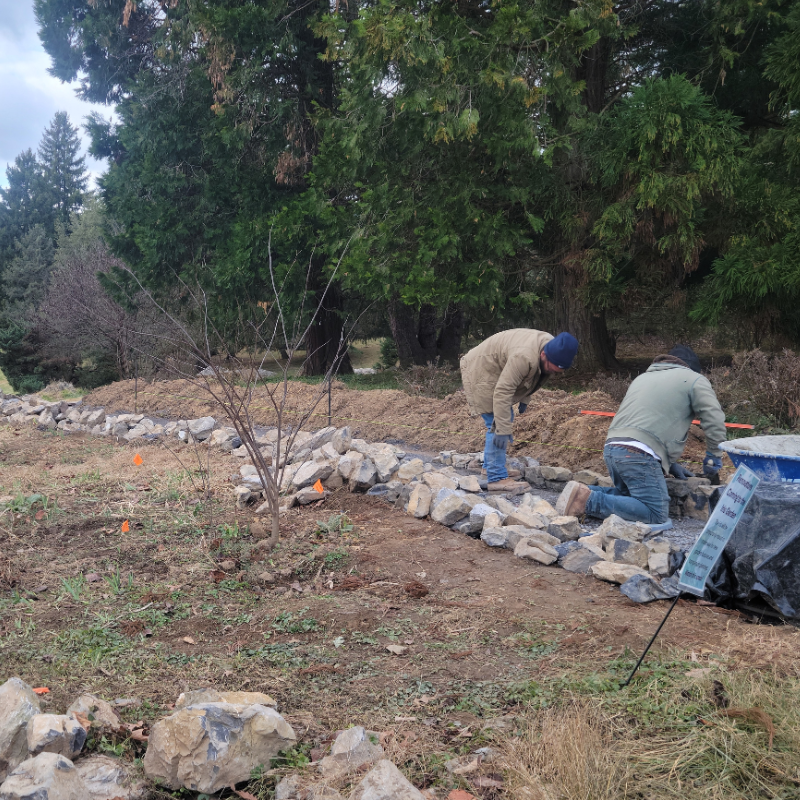 Two men building a stone wall.